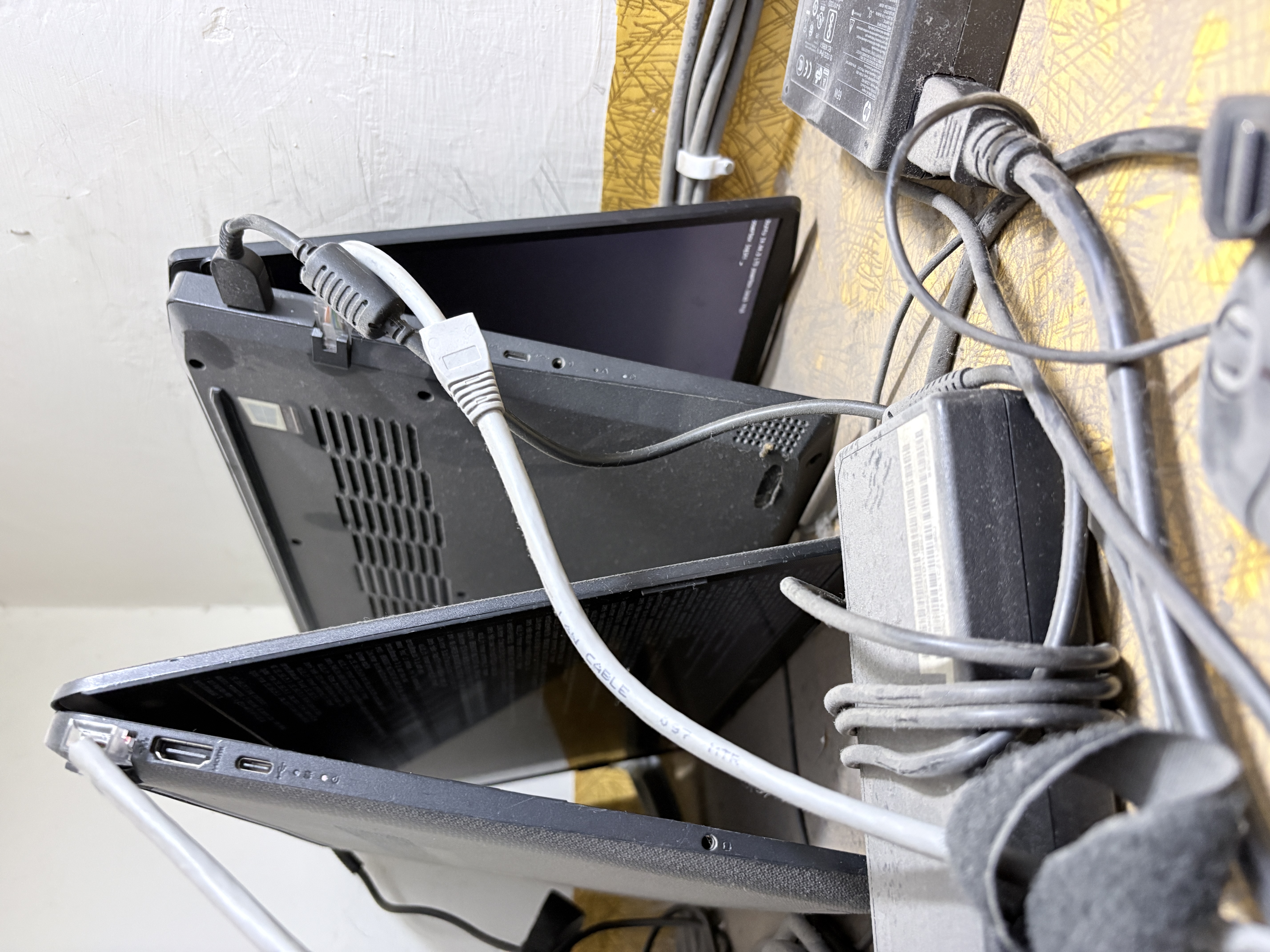 The two machines standing upright — ethernet cables, power bricks, and a healthy amount of dust